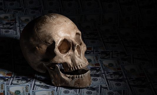 Human skull against the background of 100 US dollar bills