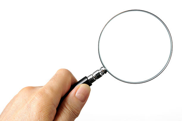 Isolated shot of holding a magnifying glass on white background Left hand holding a magnifying glass isolated on white background. magnifying glass photos stock pictures, royalty-free photos & images