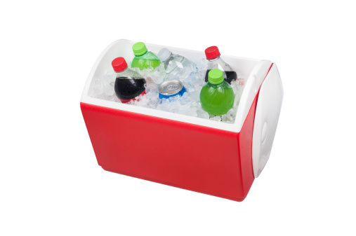 An isolated ice chest cooler filled with ice and soft drinks such as water and soda.