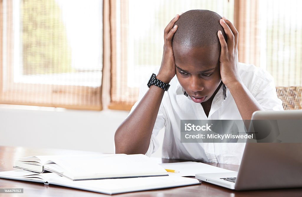 A young man who is stressed out at schoolwork A young student at his desk looking stressed about his work Teenager Stock Photo