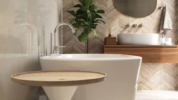 istock Round wooden side table, bathtub, fiddle leaf fig tree in luxury design bathroom in sunlight on beige brown tile wall 1666766822