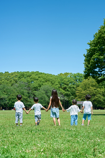 Rear view of children holding hands in a row on the meadow