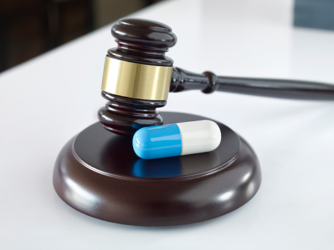Pill on a gavel on top of a desk in a court room