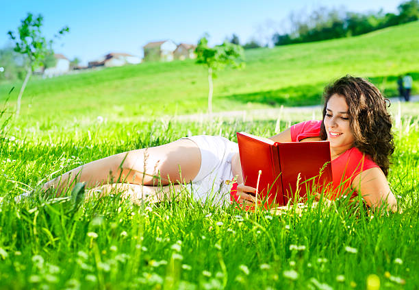 istock Young Woman lying on the grass and reading 166678236