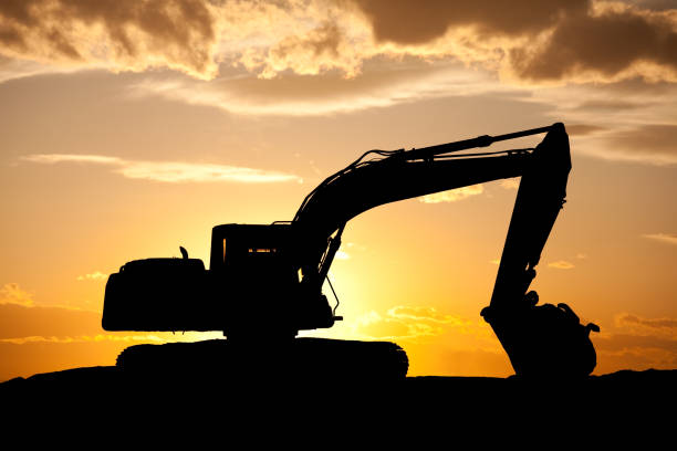 Crawler excavators silhouette are digging the soil in the construction site. on  sunset background