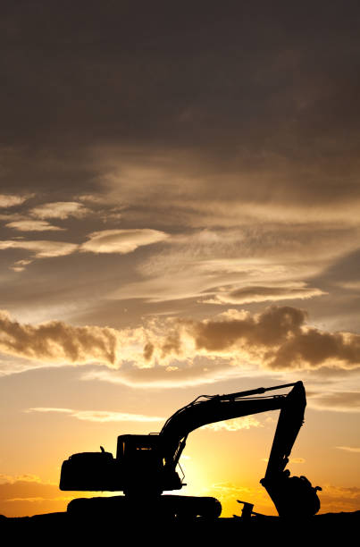 Crawler excavators silhouette are digging the soil in the construction site. on  sunset background