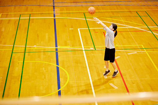 Japanese woman playing basketball in the gym