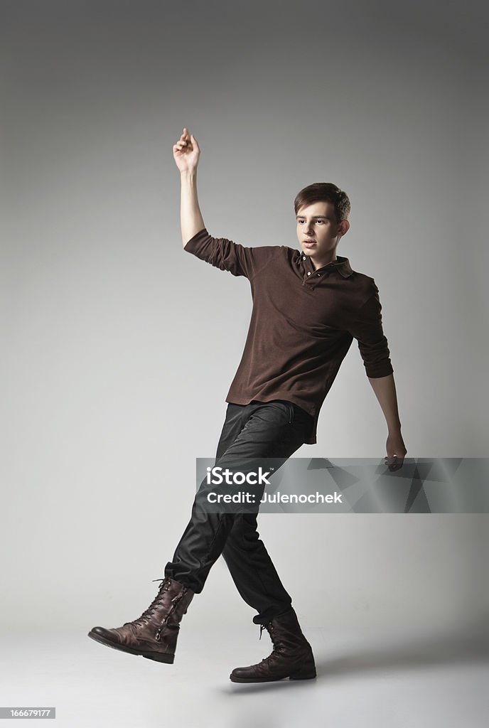 Young fashion male jumping on grey background Full length portrait of a young fashion male jumping on grey background Adult Stock Photo