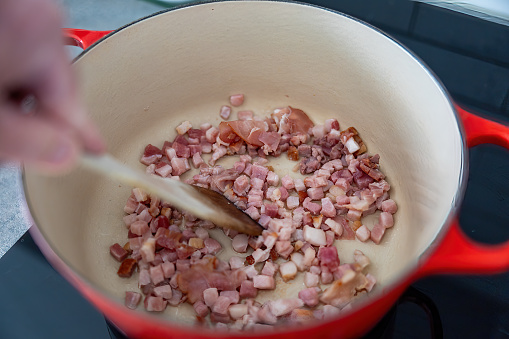 Pancetta and bacon bits frying in a saucepan