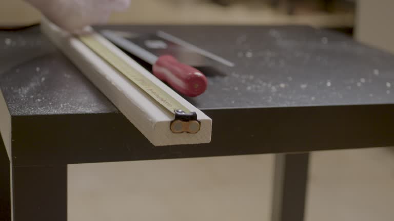 Static shot of a worker measuring and marking a plank of wood ready to be cut in a workshop