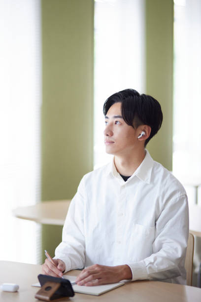 istock Japanese college student male studying using smartphone in university library 1666867647
