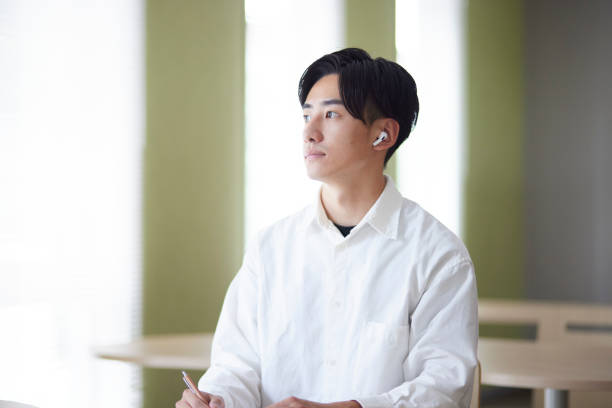 istock Japanese college student male studying using smartphone in university library 1666867649