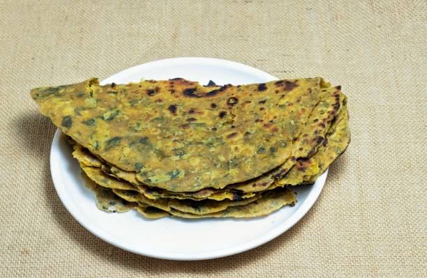 istock Methi Paratha or Fenugreek Paratha in a White Plate Isolated on Burlap Fabric 1666917312