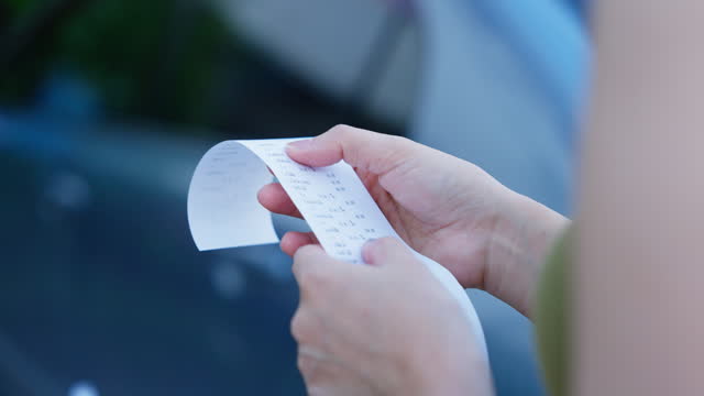 Close-up shot of female shopper checking receipt She calculates the money and checks its accuracy