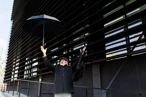 Portrait of senior businessman with umbrella walking