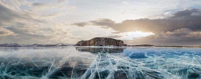 Transparent ice on Lake Baikal. Baikal lake in winter with transparent cracked blue ice. The ice of Lake Baikal. Winter Siberian landscape.