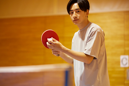 Japanese college student man practicing table tennis in the gym