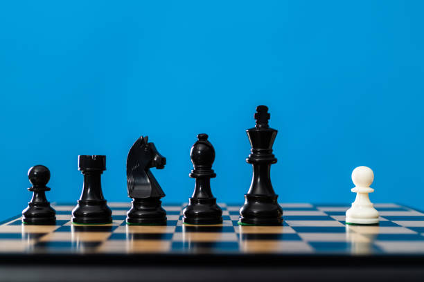 White chess pawn and black pieces on chess board.