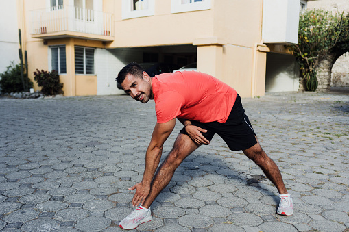 Latin man exercising and stretching in city street in Mexico Latin America, hispanic people outdoors