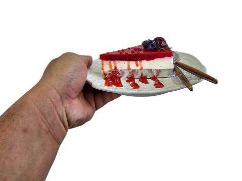 Isolated Hand holding Cheesecake topped with raspberries on white plate on white background.