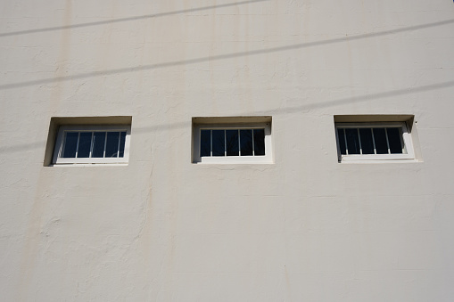 Low angle view of three small windows in a gray wall