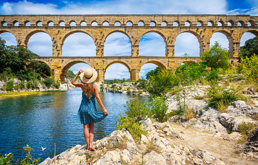 Woman tourist with dress and hat enjoying the Pont du Gard in France