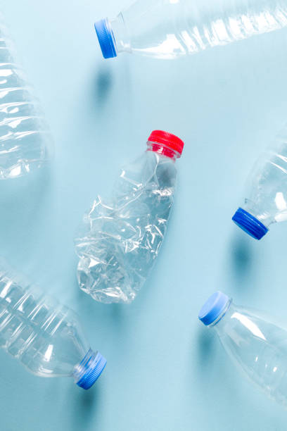 istock Crushed plastic water bottles with blue caps standing around crushed plastic water bottle with red cap on blue background 1667161353