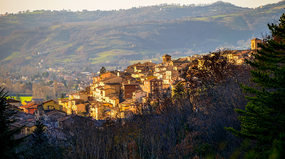 A townscape of Gualdo Tadino, a medieval village in the Italian region of Umbria surrounded by coniferous forests. An important town since Roman times, Gualdo Tadino rises along the ancient consular Flaminia route. The Umbria region, considered the green lung of Italy for its wooded mountains, is characterized by a perfect integration between nature and the presence of man, in a context of environmental sustainability and healthy life. In addition to its immense artistic and historical heritage, Umbria is famous for its food and wine production and for the high quality of the olive oil produced in these lands. Image in 16:9 ratio and high definition quality.