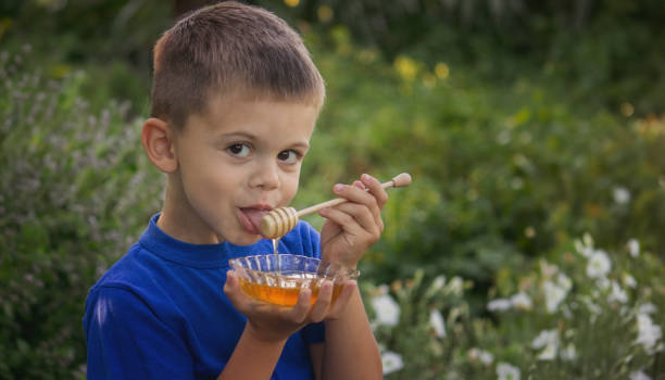 istock boy eats honey in nature, homemade honey. Selective focus 1667178111