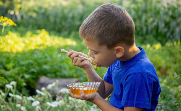 istock boy eats honey in nature, homemade honey. Selective focus 1667178117