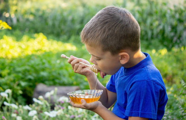 istock boy eats honey in nature, homemade honey. Selective focus 1667178254