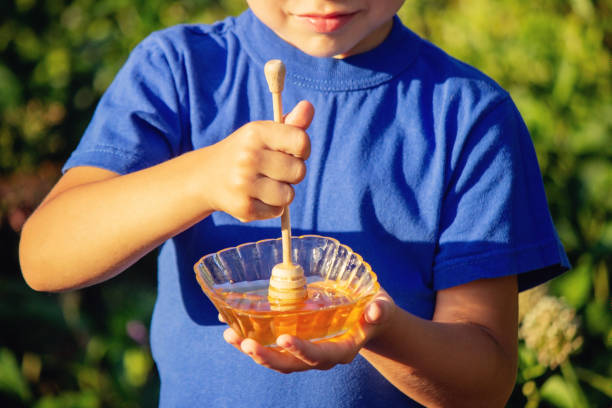 istock boy eats honey in nature, homemade honey. Selective focus 1667178397