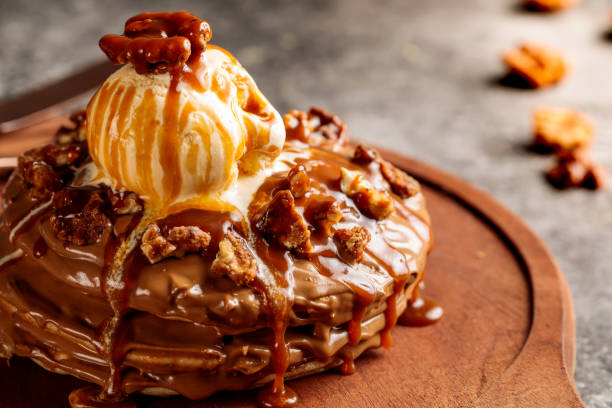 Praline pecan pancake with hot chocolate served in wooden board isolated on background top view of cafe baked food