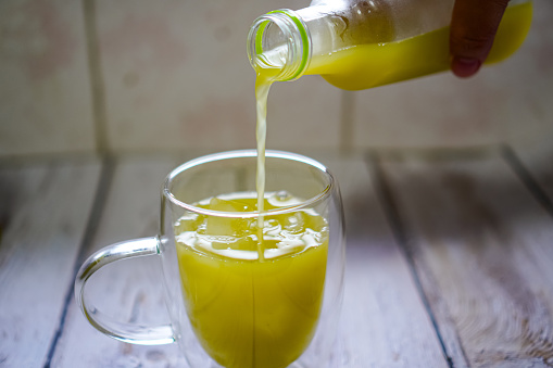 Picture showing freshly chilled sugarcane juice being poured into clear glasses placed on wooden tableware, molasses.