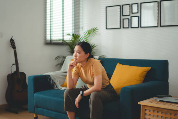 istock Asian woman feeling lonely thinking about problem sitting on sofa. 1667199641