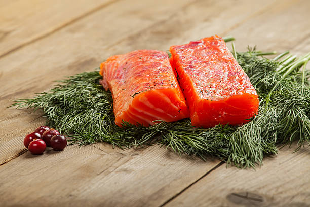 Salty salmon with cranberry Two pieces of salty salmon with greenery and cranberry on the old wooden table gravad stock pictures, royalty-free photos & images