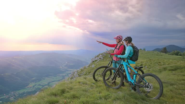 SLO MO DS Two female mountain bikers looking at the map on the phone while standing on the mountain