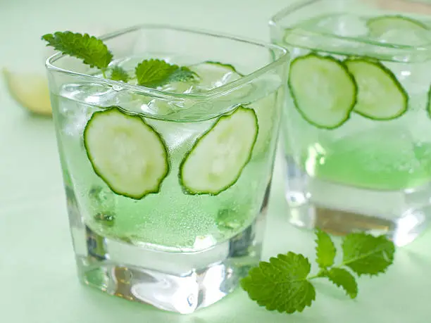 Cold fresh lemonade with cucumber and ice, selective focus