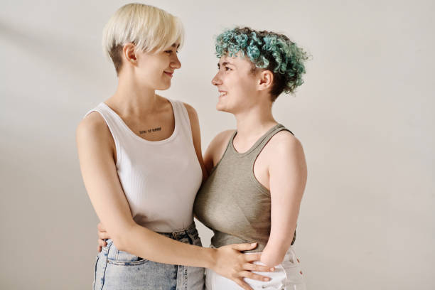 Lesbian girl embracing her girlfriend with disability against white background