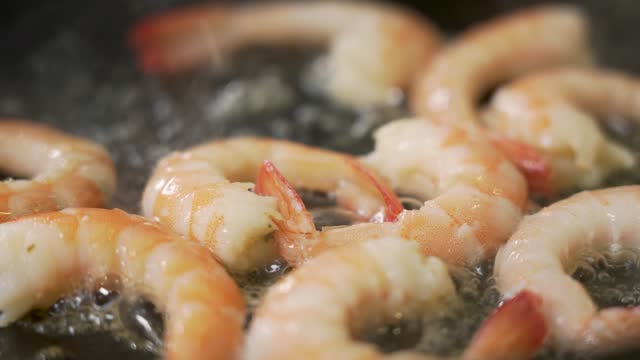 Chef is frying shrimps on a pan