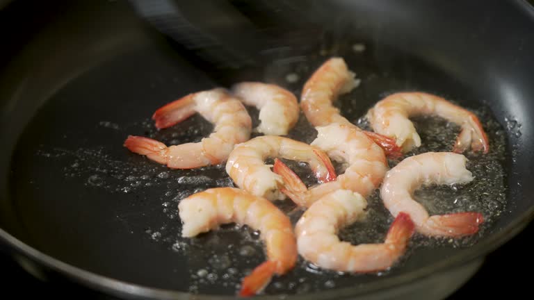 Chef is frying shrimps on a pan