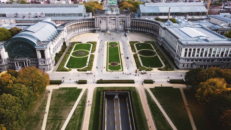 Aerial View of two cars driving on a road going under the Cinquantenaire in Brussels, Belgium tracking shot wide