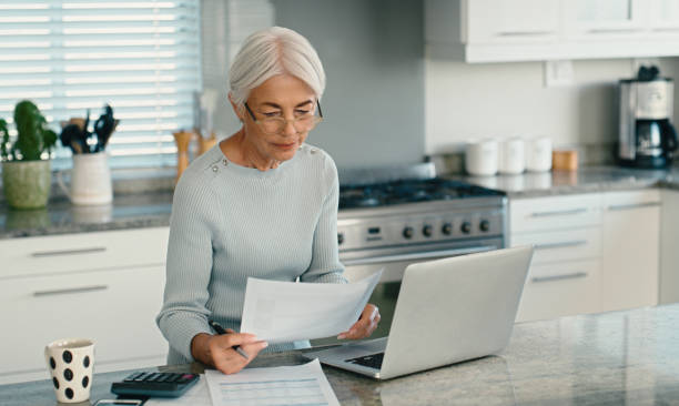 Mature woman, bills and documents on laptop for home mortgage, budget planning and pension research. Freelancer or person on computer, reading paperwork or taxes, asset management and life insurance mujer madura, facturas y documentos en computadora portátil para hipotecas de viviendas, planificación presupuestaria e investigación de pensiones. freelancer o persona en computadora, leyendo papeleo o impuestos, administración de activos y seguro de