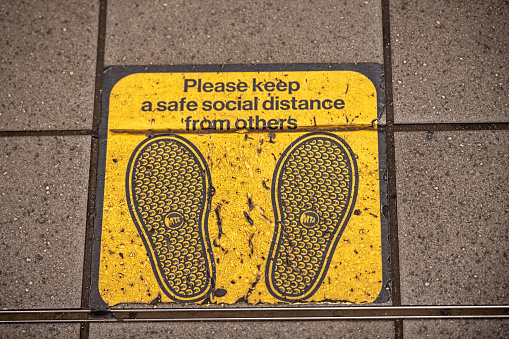 Queens Plaza Subway Station, Queens, New York, USA - August 12th 2023:   Warning sign on the floor at a subway station to make people keep a safe distance to each other