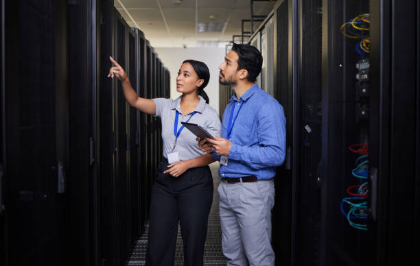 istock People, server room and engineering teamwork, inspection and tablet for cybersecurity, power or coding solution. Electrician man and woman or manager show or check data center with digital technology 1667370657