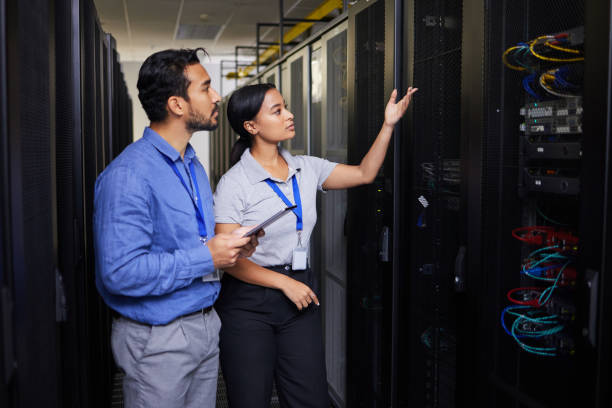 istock People, data center and engineering teamwork, inspection and cybersecurity, power or backup solution with tablet. Electrician man, woman or manager show or check cables in server room with technology 1667370663