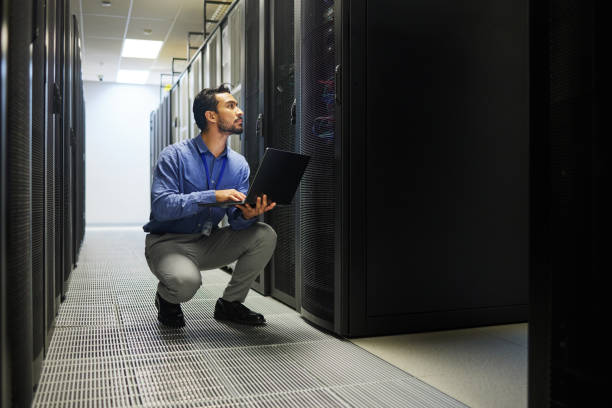 istock Server room, laptop or man typing for cybersecurity glitch, machine or to search online on servers system. IT support, data center or male engineer fixing network for information technology solution 1667372302