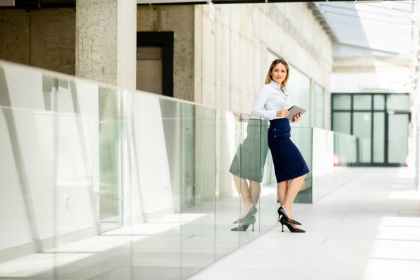 istock Young woman working on digital tablet in the office hallway 1667374498