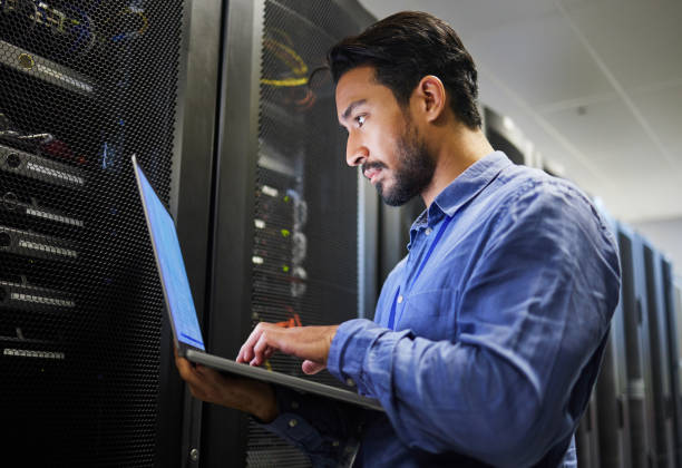 istock Connectivity, data center and a man with a laptop for maintenance, cyber security and internet check. Coding, email and an Asian programmer typing on a computer for network or server analytics 1667382510