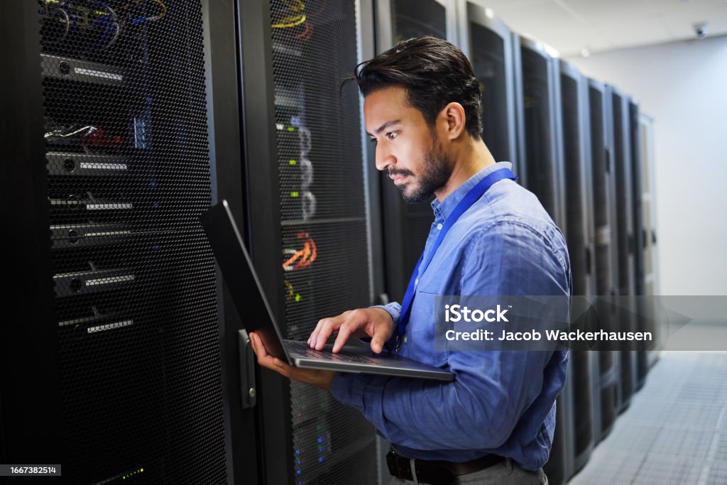 Programming, data center and a man with a laptop for maintenance, cyber security and internet check. Coding, email and an Asian programmer typing on a computer for network or server analytics Network Security Stock Photo Programming, data center and a man with a laptop for maintenance, cyber security and internet check. Coding, email and an Asian programmer typing on a computer for network or server analytics Network Security Stock Photo